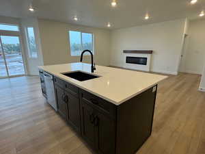 Kitchen featuring open floor plan, recessed lighting, light wood-type flooring, a center island with sink, and dishwasher