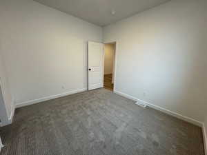 Unfurnished room featuring dark carpet and baseboards