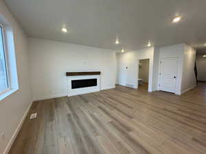 Unfurnished living room featuring a fireplace, light wood-type flooring, and recessed lighting