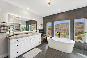 Bathroom with tile walls, vanity, a freestanding tub, recessed lighting, and a mountain view