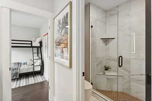 Ensuite bathroom featuring a shower stall and wood finished floors