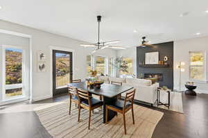 Dining space with recessed lighting, a large fireplace, dark wood finished floors, and ceiling fan