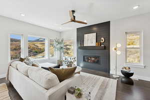 Living room with recessed lighting, dark wood finished floors, a large fireplace, and ceiling fan