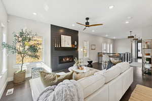 Living area with recessed lighting, dark wood-type flooring, ceiling fan, and a fireplace