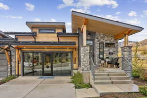 View of exterior entry with concrete driveway, a garage, and stone siding
