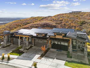 Contemporary home featuring a standing seam roof, a metal roof, concrete driveway, and stone siding