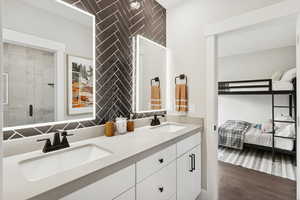 Ensuite bathroom with double vanity, a stall shower, and dark wood finished floors