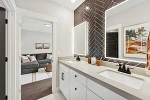 Ensuite bathroom featuring double vanity, decorative backsplash, recessed lighting, and light wood-type flooring
