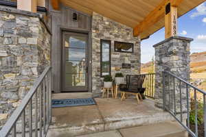 Doorway to property featuring stone siding and covered porch