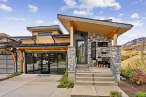 Doorway to property featuring stone siding, driveway, and a garage