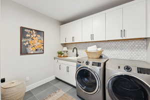 Laundry area featuring dark tile patterned flooring, separate washer and dryer, and cabinet space
