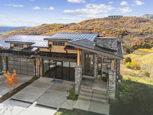 Contemporary home with a standing seam roof, a metal roof, stone siding, a mountain view, and driveway