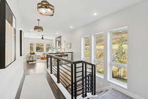 Corridor with an upstairs landing, recessed lighting, and dark wood-style flooring