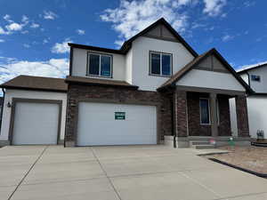 View of front of house featuring covered porch, stucco siding, driveway, and brick siding
