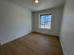 Spare room with light wood finished floors and a textured ceiling
