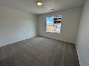 Carpeted empty room featuring baseboards and a textured ceiling