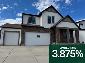 View of front facade with stucco siding, brick siding, driveway, and covered porch
