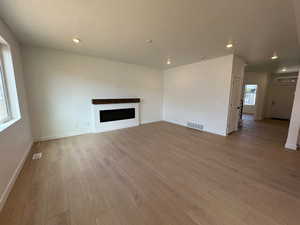 Unfurnished living room with a textured ceiling, light wood-type flooring, a fireplace, and recessed lighting