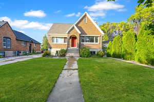 View of front facade featuring a chimney, roof with shingles, and a front lawn