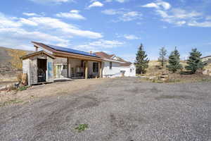 Rear view of property with solar panels, a patio area, an outdoor structure, and board and batten siding