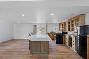 Kitchen with a kitchen breakfast bar, glass insert cabinets, freestanding refrigerator, a center island, and recessed lighting