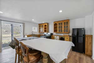 Kitchen featuring freestanding refrigerator, a kitchen bar, recessed lighting, light countertops, and a kitchen island