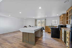 Kitchen featuring recessed lighting, a center island, electric range, light wood-style floors, and brown cabinets