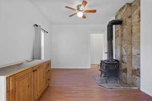 Living room with a wood stove, light wood-style floors, and ceiling fan