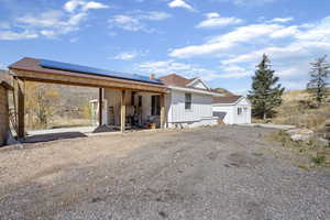 View of front facade with solar panels, board and batten siding, a shingled roof, and a patio