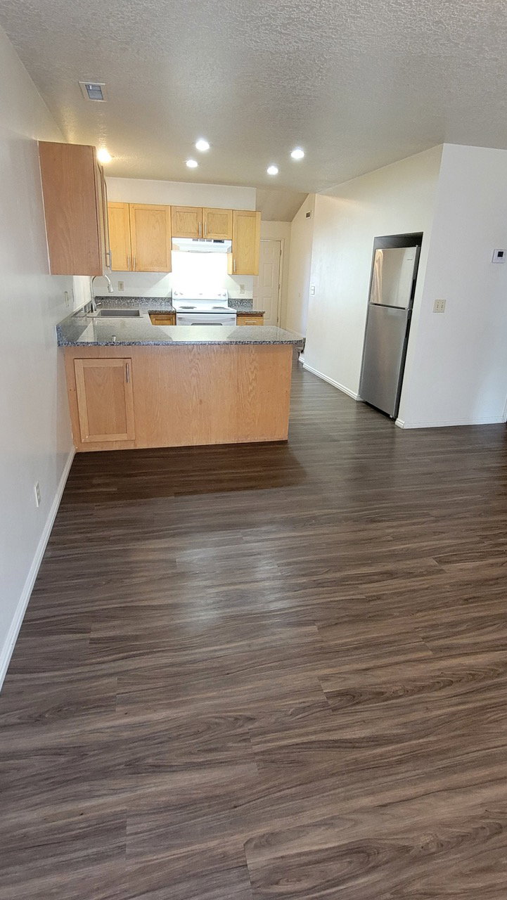 Kitchen featuring a peninsula, a textured ceiling, dark wood-type flooring, freestanding refrigerator, and electric stove
