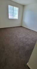 Empty room with baseboards and dark colored carpet