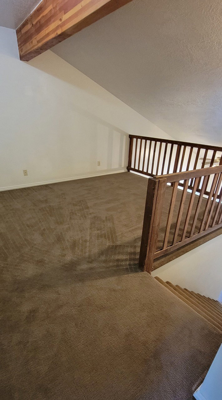 Stairway featuring a textured ceiling and carpet floors