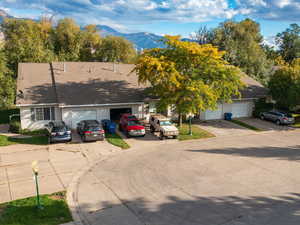 View of front facade with a mountain view, driveway, and roof with shingles