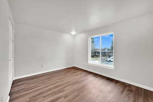 Unfurnished room with dark wood-style flooring and baseboards