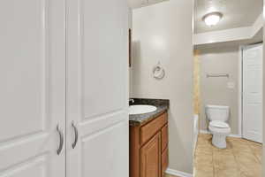 Full bathroom with vanity, a textured ceiling, light tile patterned floors, and tub / shower combination