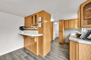 Kitchen with glass insert cabinets, a kitchen breakfast bar, light wood finished floors, and tile counters