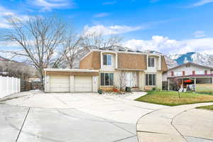 View of front facade with a mountain view, brick siding, concrete driveway, a shingled roof, and mansard roof