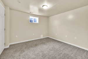 Carpeted empty room featuring baseboards and a textured ceiling