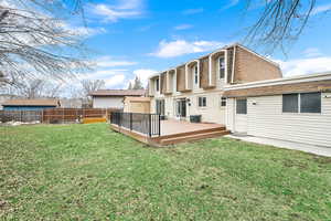 Back of house with a wooden deck, a shingled roof, a fenced backyard, brick siding, and mansard roof