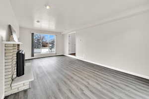 Unfurnished living room featuring a brick fireplace and wood finished floors
