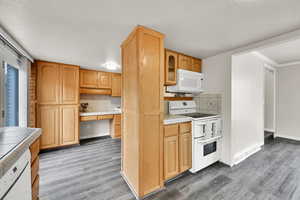 Kitchen featuring built in desk, tasteful backsplash, tile countertops, and white appliances
