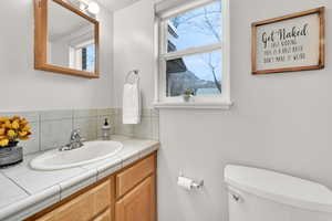 Half bath featuring vanity, healthy amount of natural light, and decorative backsplash