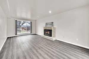 Unfurnished living room with wood finished floors, a fireplace, and recessed lighting