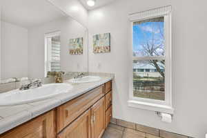 Full bath featuring light tile patterned floors and double vanity