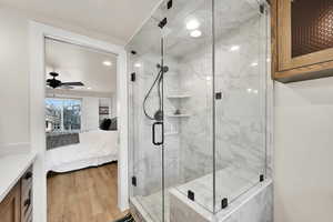 Full bath with connected bathroom, a marble finish shower, light wood finished floors, vanity, and a ceiling fan