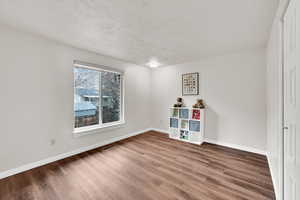 Empty room with wood finished floors and a textured ceiling