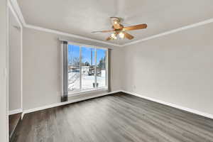 Spare room with crown molding, wood finished floors, and ceiling fan