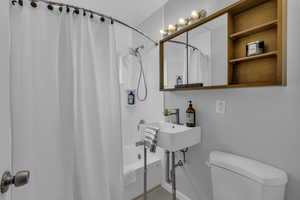 Full bathroom with toilet and shower / bath combo with shower curtain