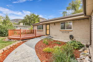 Doorway to property with a deck with mountain view and brick siding