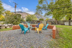 Fenced backyard with a mountain view, an outdoor fire pit, a storage unit, and a patio